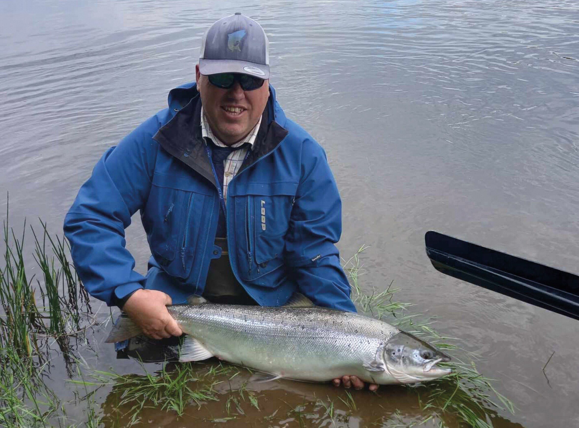 Head ghillie Martin kneeling in the river holding a fresh salmon
